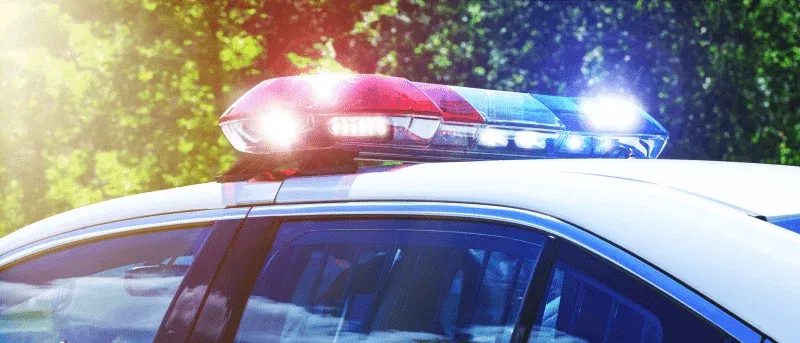 A close-up of a police car's flashing red and blue lights on a sunny day.